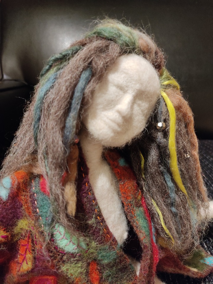 unique needlefelt artdoll commision called "I am". She has long hair with coloured stands and rich coloured coat and a wistful gaze.