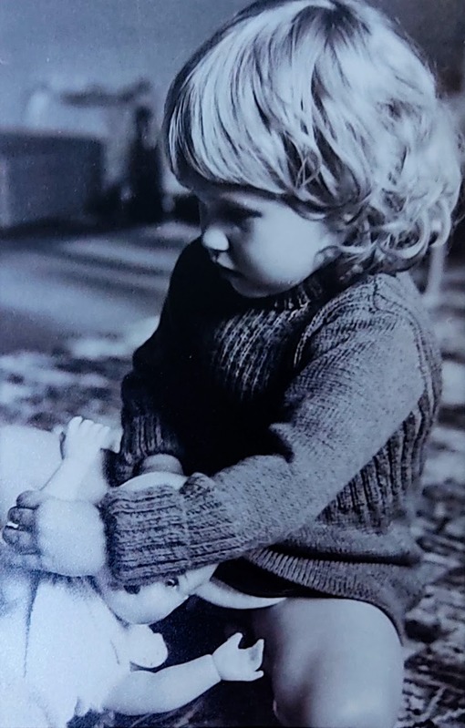 black and white image of gillian as a young girl, playing with a doll